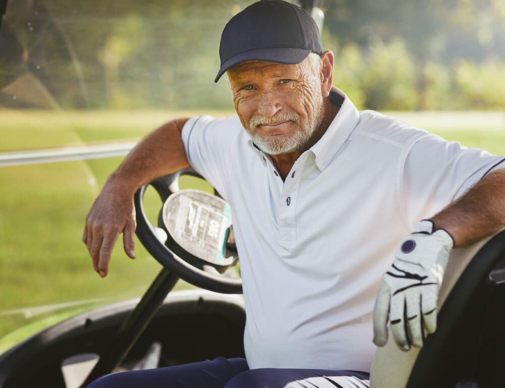 Older man in a golf cart on golf course