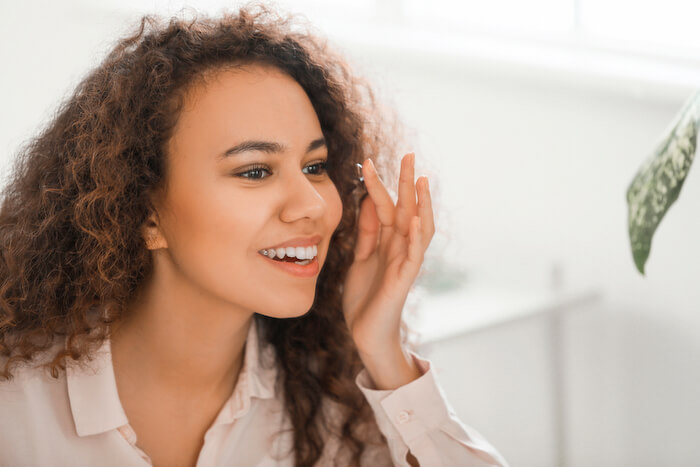 young woman putting a contact lens in her eye