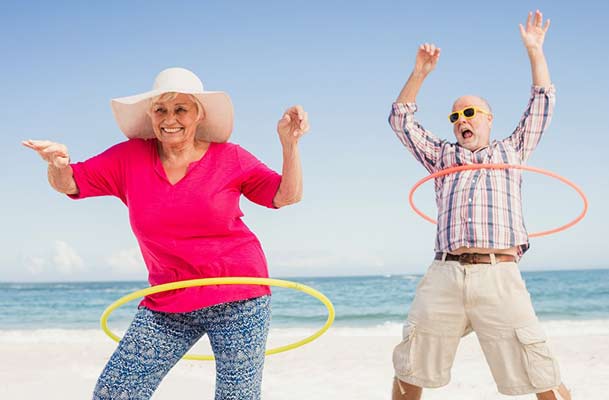 Older couple having fun on a beach with hula hoops