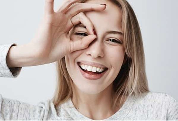 Happy woman giving the "ok" hand sign around eye