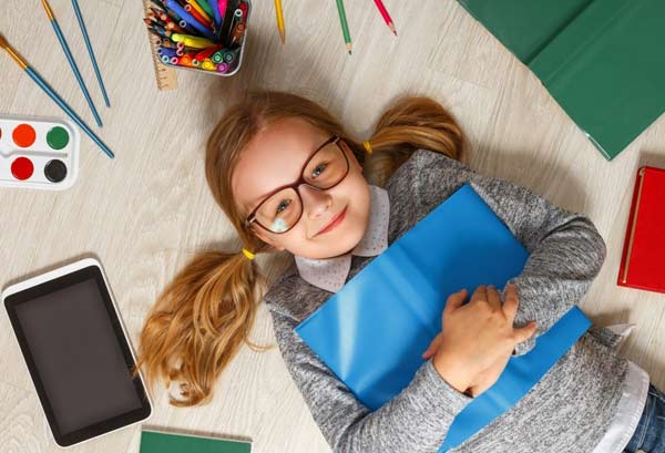 Little girl with glasses and school supplies